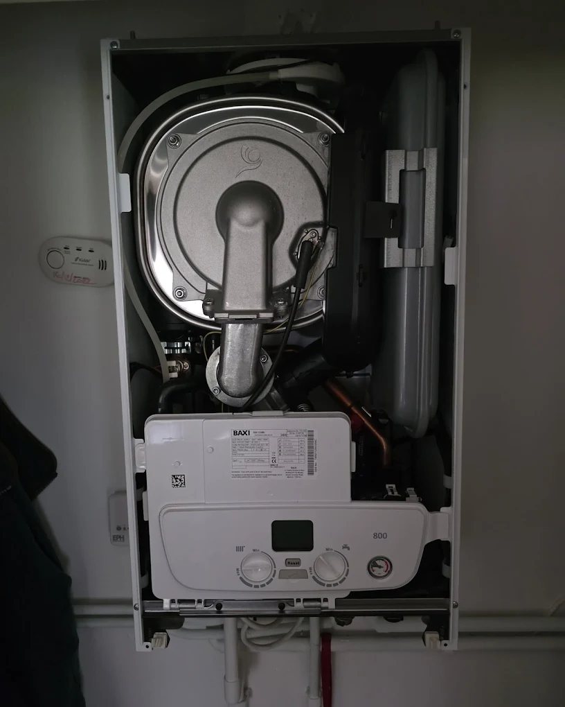 Baxi 800 combi boiler with the front casing removed showing the fan, heat exchanger and controls during a service
