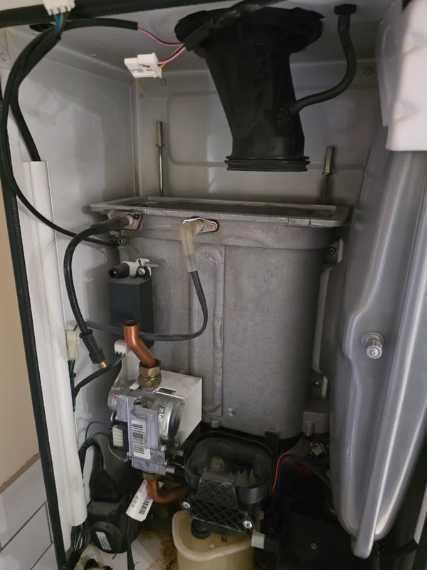 Interior of a gas boiler showing the heat exchanger, fan and gas valve during a service