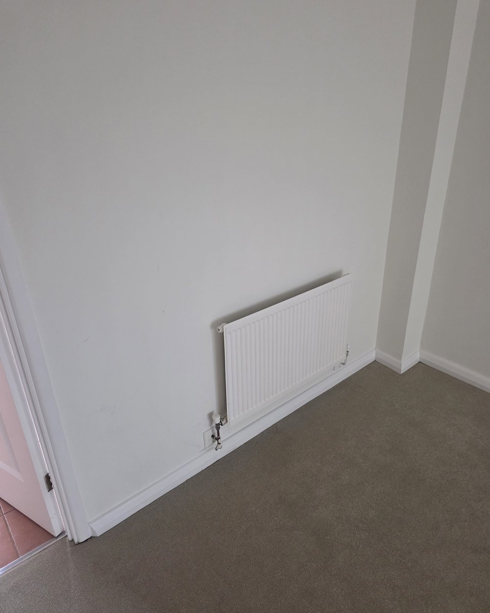 White panel radiator neatly installed with a thermostatic valve in a freshly decorated room