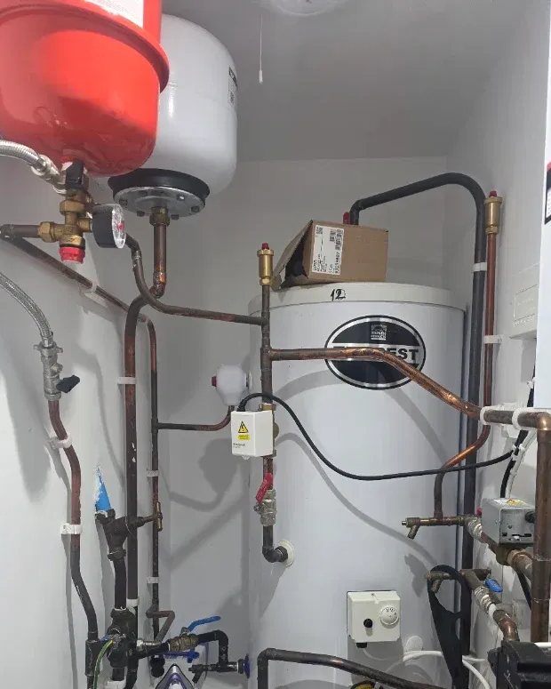 Neat unvented hot water cylinder installation with copper pipework, expansion vessel and heating controls by S.M Gas Utilities
