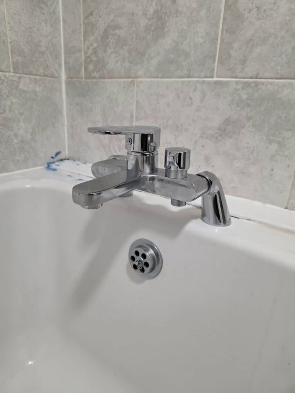 Chrome bath and shower mixer tap fitted to a white bath with tiled surround